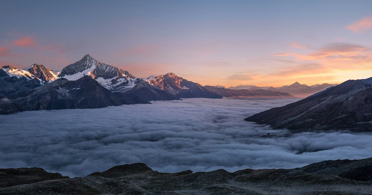 Montagnes enneigées dans une mer de nuages au coucher du soleil